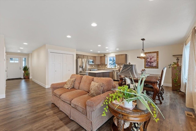 living room with recessed lighting, visible vents, baseboards, and wood finished floors