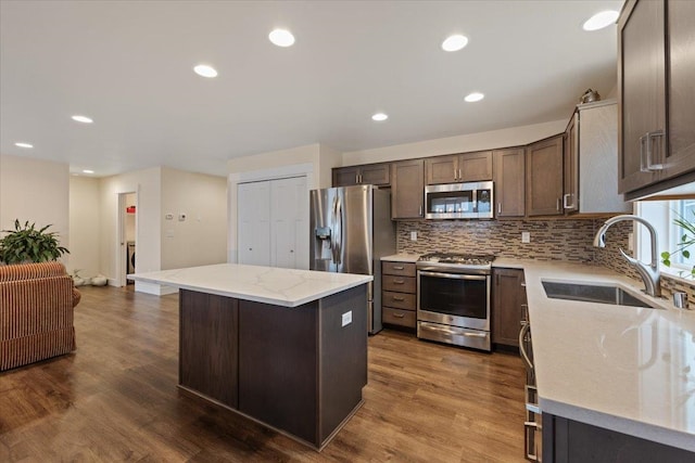 kitchen featuring stainless steel appliances, a kitchen island, a sink, and dark wood finished floors