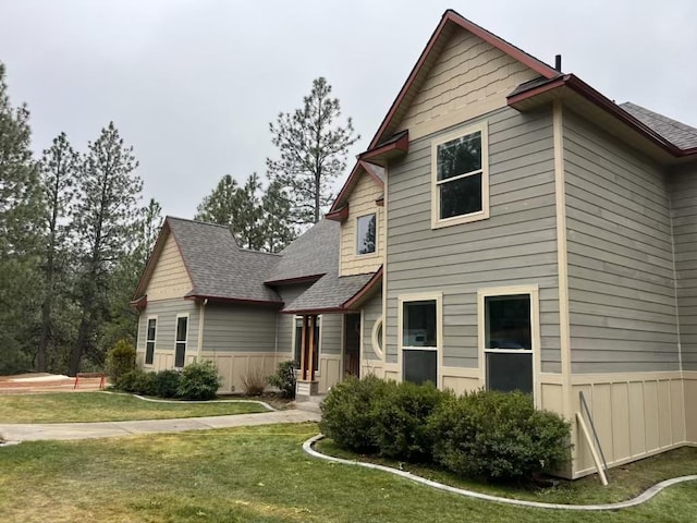 view of front of property with a shingled roof and a front yard