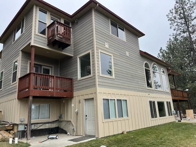 rear view of property featuring a lawn and a balcony