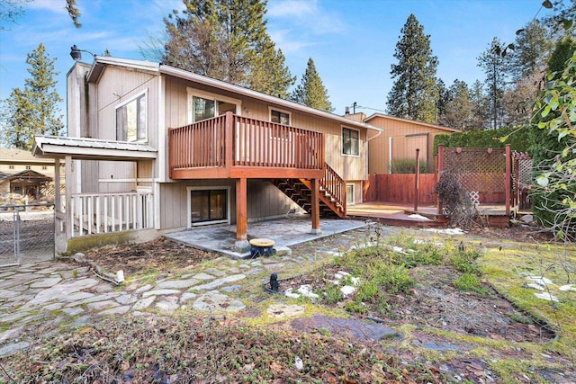 back of property featuring a chimney, fence, a deck, and a patio