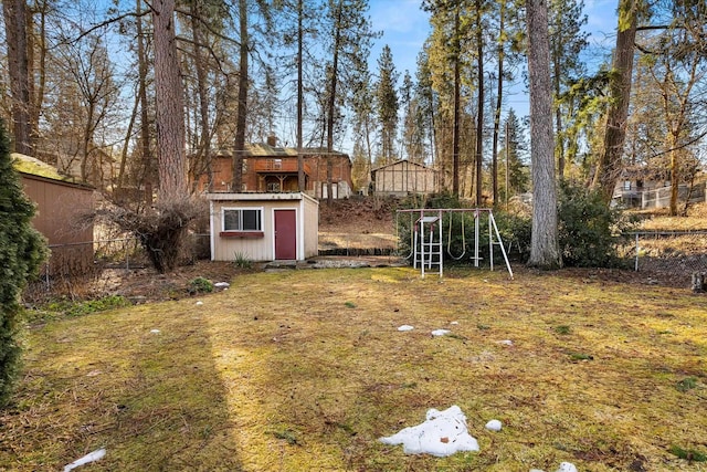 view of yard featuring a shed, a playground, fence, and an outdoor structure