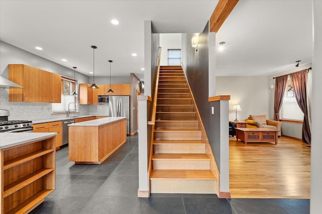 kitchen with tasteful backsplash, a center island, stainless steel appliances, light countertops, and a sink