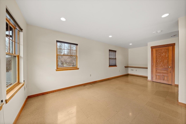 spare room with light floors, recessed lighting, plenty of natural light, and baseboards