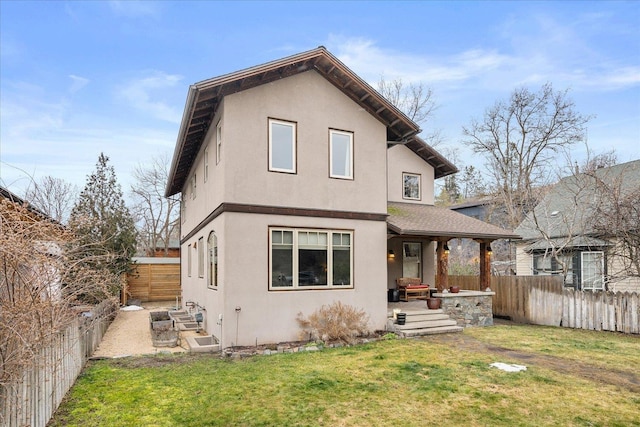 back of house featuring a lawn, a fenced backyard, and stucco siding