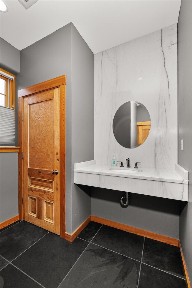 bathroom featuring tile patterned floors, a sink, and baseboards