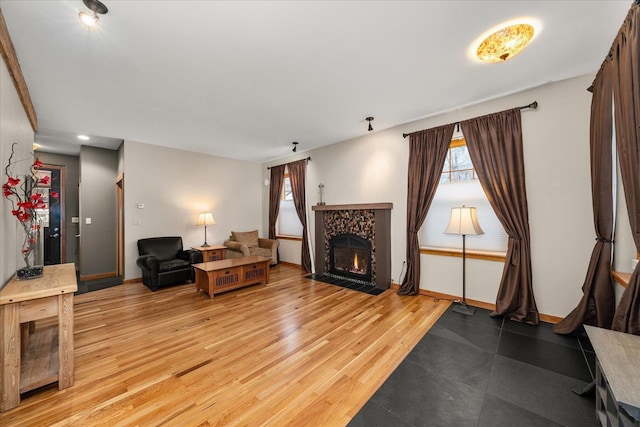 living area with a fireplace with flush hearth, baseboards, and light wood-style flooring