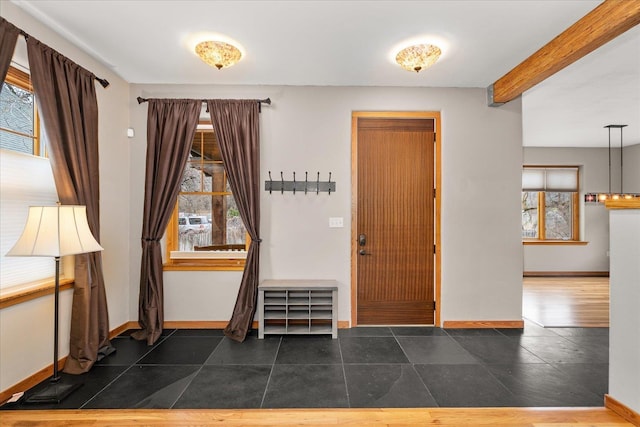 foyer with beam ceiling and baseboards