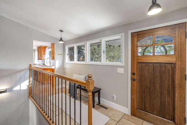 foyer entrance with baseboards and vaulted ceiling