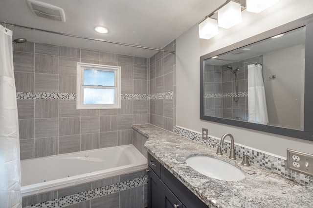 bathroom featuring a combined bath / shower with jetted tub, visible vents, and vanity