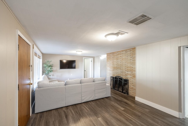 living room with baseboards, a fireplace, visible vents, and wood finished floors