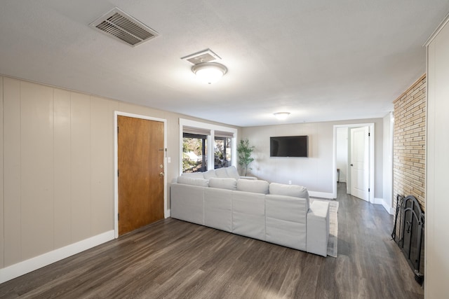 living area with a brick fireplace, visible vents, baseboards, and wood finished floors