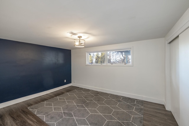 spare room with visible vents, dark wood finished floors, and baseboards