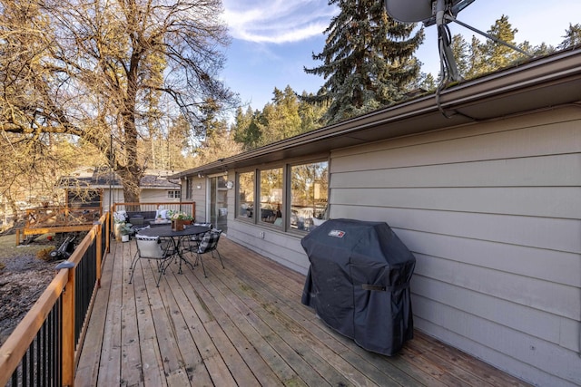 wooden terrace featuring outdoor dining area and a grill