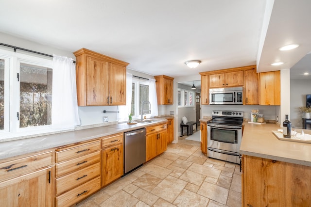 kitchen featuring stainless steel appliances, light countertops, a sink, and stone tile flooring