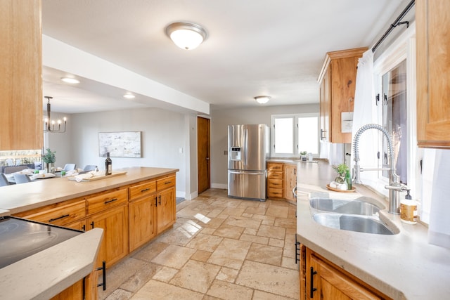 kitchen with stone tile floors, stainless steel fridge with ice dispenser, light countertops, a sink, and baseboards