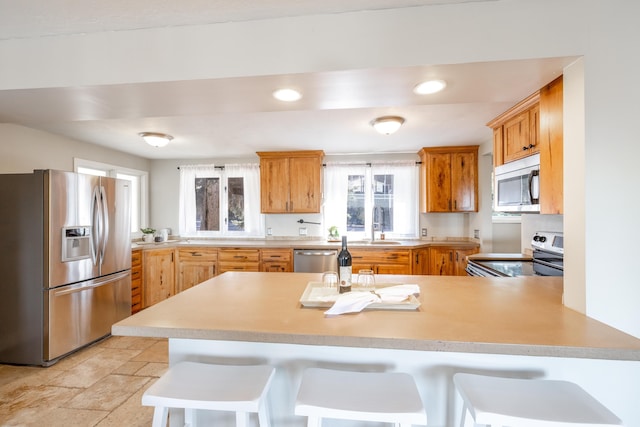 kitchen featuring recessed lighting, light countertops, appliances with stainless steel finishes, a sink, and a peninsula