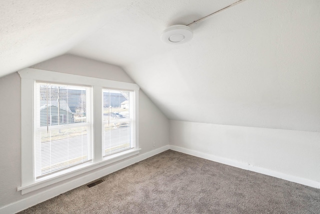 bonus room with baseboards, visible vents, vaulted ceiling, and carpet flooring