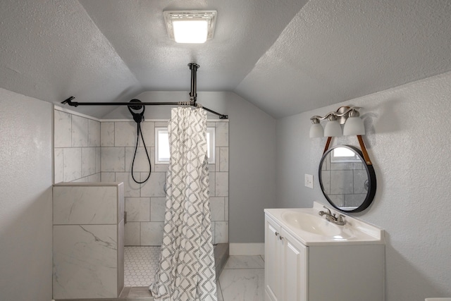 bathroom featuring marble finish floor, lofted ceiling, vanity, a textured ceiling, and tiled shower