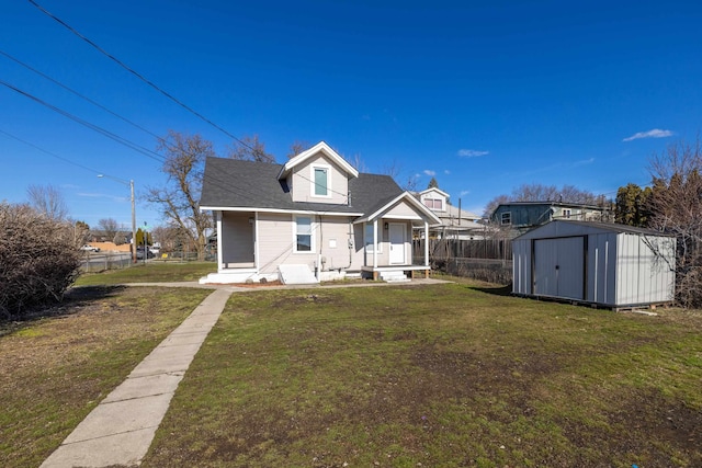 rear view of house with a storage unit, a lawn, an outdoor structure, and fence