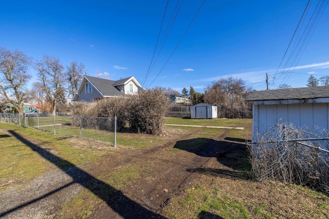 view of yard featuring a storage shed, an outdoor structure, and fence