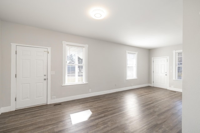 spare room with dark wood-style floors, visible vents, and baseboards