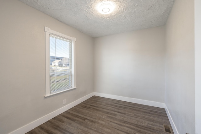 unfurnished room with baseboards, a textured ceiling, visible vents, and dark wood-style flooring