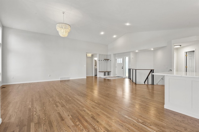 unfurnished living room with light wood-style floors, visible vents, vaulted ceiling, and an inviting chandelier