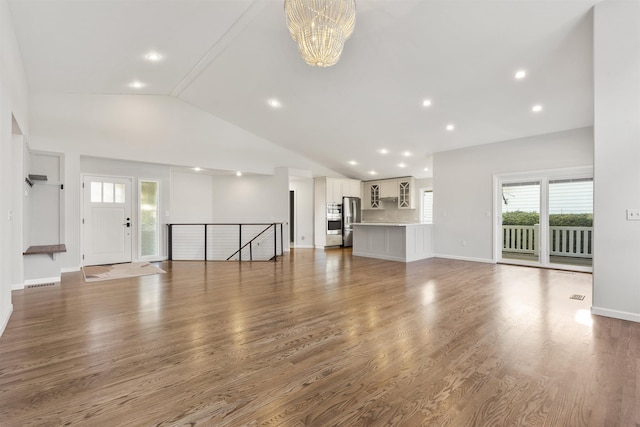unfurnished living room with baseboards, a chandelier, wood finished floors, and recessed lighting