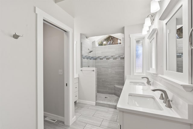 bathroom with double vanity, walk in shower, and a sink