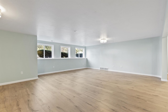 unfurnished room featuring light wood-type flooring, visible vents, and baseboards