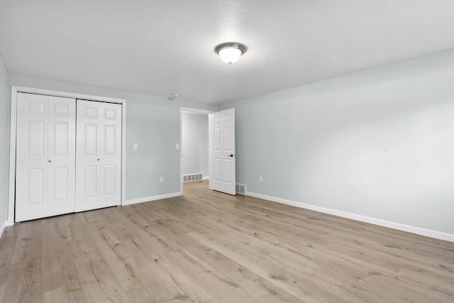 unfurnished bedroom with light wood finished floors, a closet, visible vents, and baseboards
