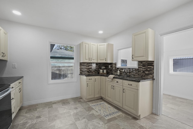 kitchen featuring dark countertops, baseboards, decorative backsplash, and cream cabinetry