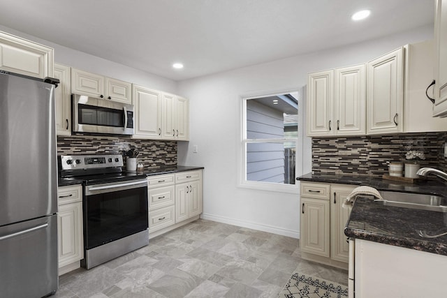 kitchen with appliances with stainless steel finishes, baseboards, decorative backsplash, and cream cabinets