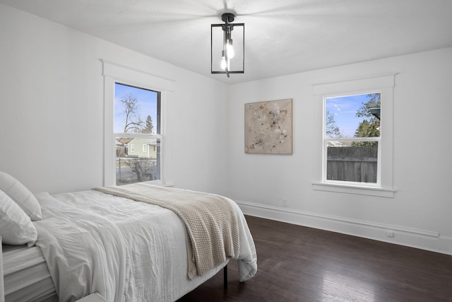 bedroom featuring dark wood-type flooring, multiple windows, and baseboards