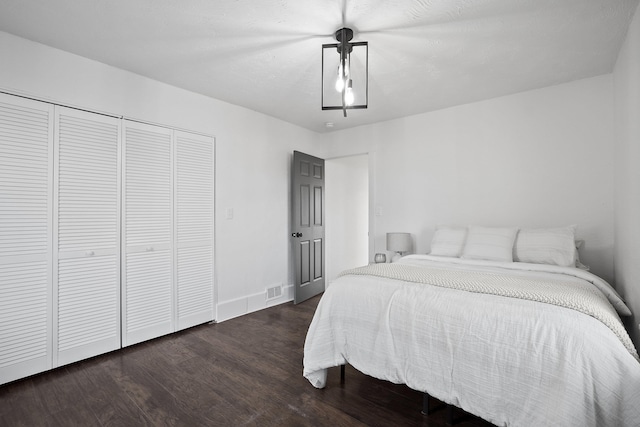 bedroom featuring dark wood-style flooring, a closet, visible vents, and baseboards