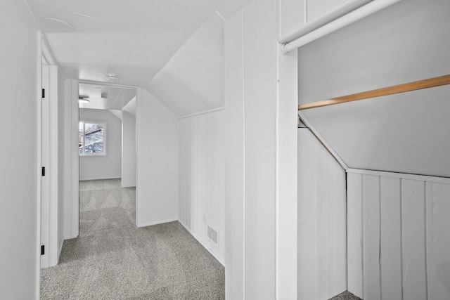 hallway featuring carpet floors, visible vents, and vaulted ceiling