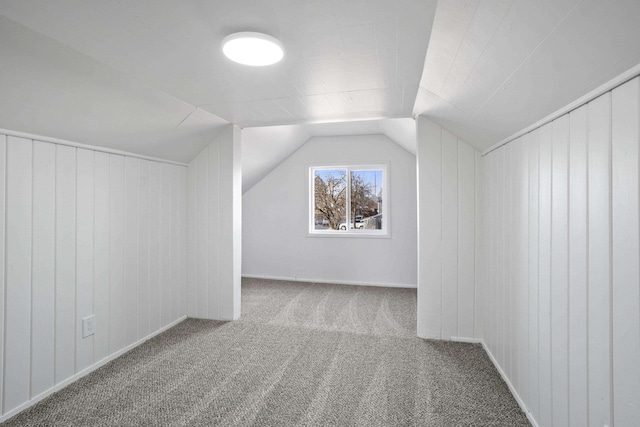 bonus room with lofted ceiling, carpet floors, and wood walls