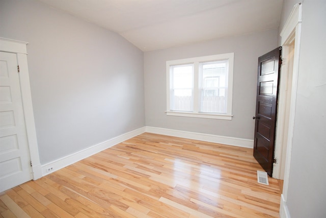 unfurnished room featuring light wood-type flooring, baseboards, visible vents, and lofted ceiling