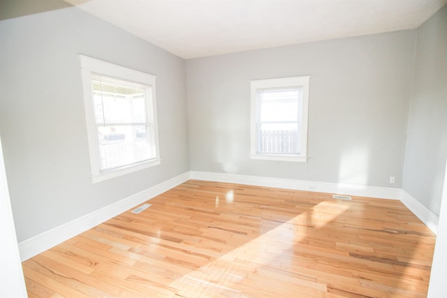 empty room featuring wood finished floors, visible vents, and baseboards