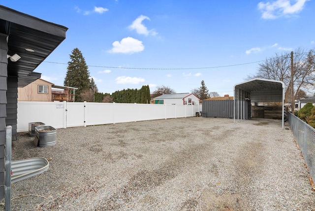 view of yard featuring a carport, driveway, fence, and a gate