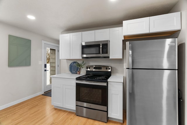 kitchen featuring light countertops, appliances with stainless steel finishes, light wood-style floors, white cabinetry, and baseboards