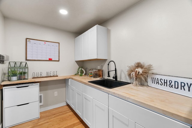 kitchen with white cabinetry, a sink, white fridge, butcher block countertops, and light wood-type flooring