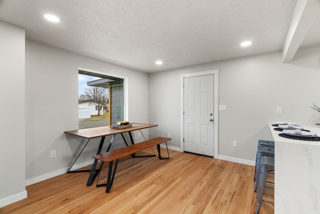 dining space with light wood-style flooring, baseboards, and a textured ceiling