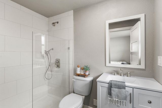 bathroom with vanity, a tile shower, and toilet