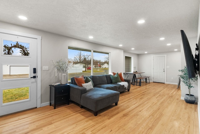 living room with recessed lighting, light wood-style flooring, and a textured ceiling