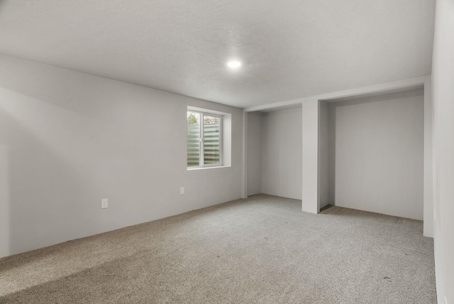 empty room with a textured ceiling and light colored carpet