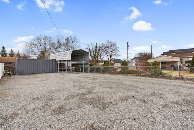 view of yard with gravel driveway, fence, and a detached carport