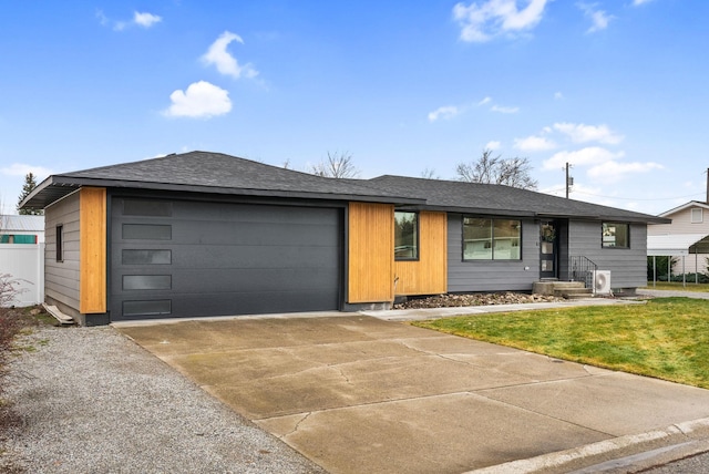 single story home featuring a garage, a shingled roof, a front lawn, and concrete driveway