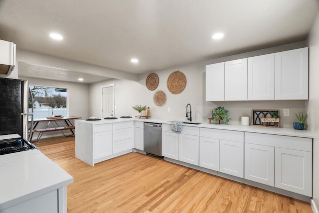 kitchen featuring a peninsula, light wood-style floors, stainless steel appliances, and a sink